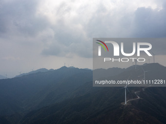 Wind turbines are standing above the rolling green mountains at the Xiutang Township wind farm in Congjiang County, Guizhou Province, China,...