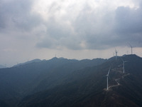 Wind turbines are standing above the rolling green mountains at the Xiutang Township wind farm in Congjiang County, Guizhou Province, China,...