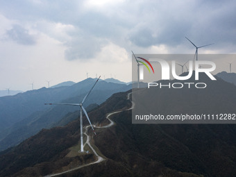 Wind turbines are standing above the rolling green mountains at the Xiutang Township wind farm in Congjiang County, Guizhou Province, China,...