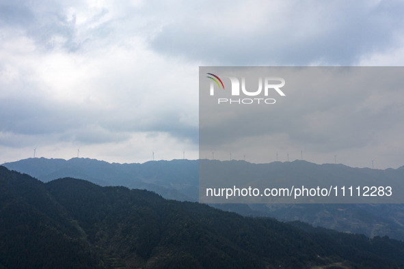 Wind turbines are standing above the rolling green mountains at the Xiutang Township wind farm in Congjiang County, Guizhou Province, China,...