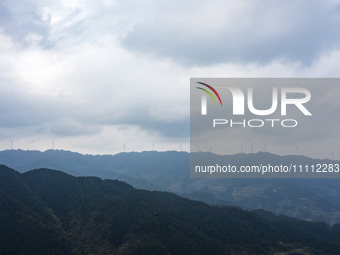 Wind turbines are standing above the rolling green mountains at the Xiutang Township wind farm in Congjiang County, Guizhou Province, China,...