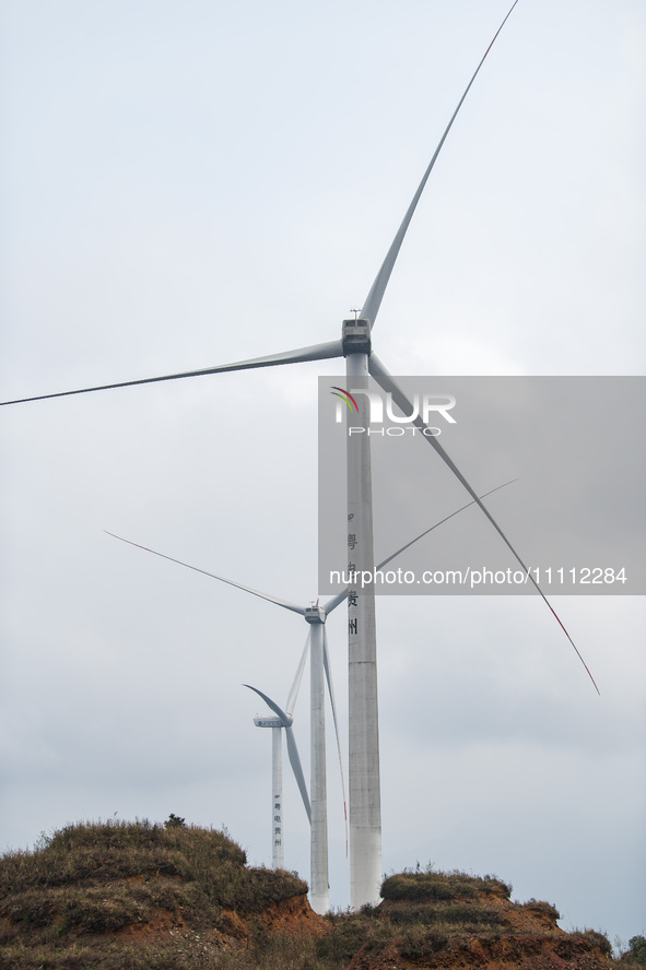 Wind turbines are standing above the rolling green mountains at the Xiutang Township wind farm in Congjiang County, Guizhou Province, China,...