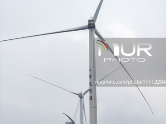 Wind turbines are standing above the rolling green mountains at the Xiutang Township wind farm in Congjiang County, Guizhou Province, China,...