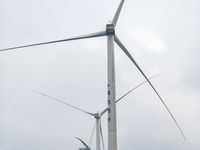 Wind turbines are standing above the rolling green mountains at the Xiutang Township wind farm in Congjiang County, Guizhou Province, China,...