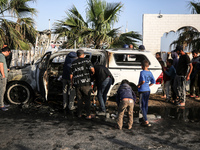 Palestinians are standing next to a vehicle in Deir Al-Balah, in the central Gaza Strip, on April 2, 2024, where employees from the World Ce...