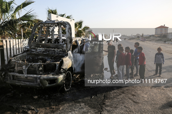 Palestinians are standing next to a vehicle in Deir Al-Balah, in the central Gaza Strip, on April 2, 2024, where employees from the World Ce...