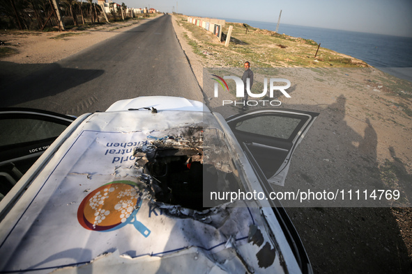 Palestinians are standing next to a vehicle in Deir Al-Balah, in the central Gaza Strip, on April 2, 2024, where employees from the World Ce...