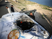 Palestinians are standing next to a vehicle in Deir Al-Balah, in the central Gaza Strip, on April 2, 2024, where employees from the World Ce...