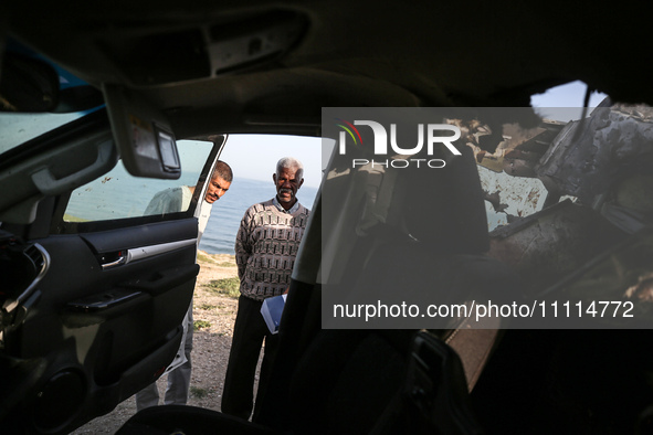 Palestinians are standing next to a vehicle in Deir Al-Balah, in the central Gaza Strip, on April 2, 2024, where employees from the World Ce...