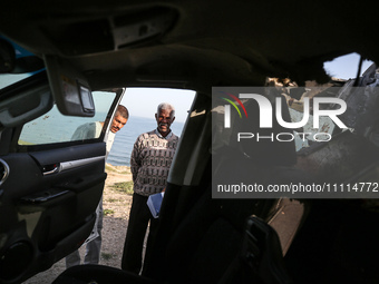 Palestinians are standing next to a vehicle in Deir Al-Balah, in the central Gaza Strip, on April 2, 2024, where employees from the World Ce...