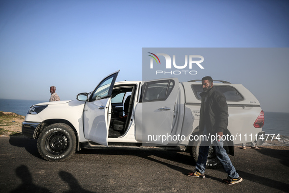 Palestinians are standing next to a vehicle in Deir Al-Balah, in the central Gaza Strip, on April 2, 2024, where employees from the World Ce...