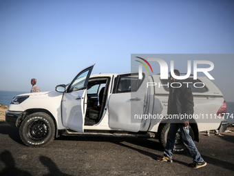 Palestinians are standing next to a vehicle in Deir Al-Balah, in the central Gaza Strip, on April 2, 2024, where employees from the World Ce...