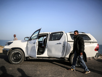 Palestinians are standing next to a vehicle in Deir Al-Balah, in the central Gaza Strip, on April 2, 2024, where employees from the World Ce...