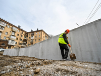 A worker is building a new modular underground bomb shelter designed for 100 people in the yard of a five-story residential building that wa...