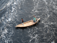 People in Bangladesh are crossing by boat over the pitch-black waters of the polluted Buriganga River in Dhaka, Bangladesh, on April 2, 2024...