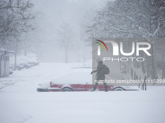 A woman is walking along a road during a snowfall in Linkoping, Sweden, on April 2, 2024. (