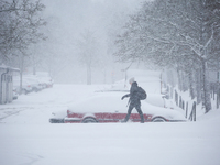 A woman is walking along a road during a snowfall in Linkoping, Sweden, on April 2, 2024. (