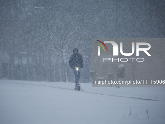 A man is riding his scooter on a road during a snowfall in Linkoping, Sweden, on April 2, 2024. (