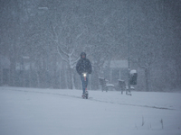 A man is riding his scooter on a road during a snowfall in Linkoping, Sweden, on April 2, 2024. (