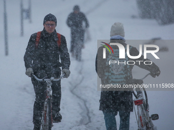 A man is riding his bike on a road during a snowfall in Linkoping, Sweden, on April 2, 2024. (