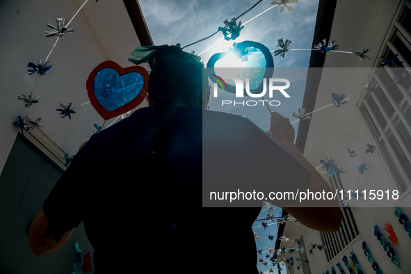 A woman is holding blue hearts made of cellophane paper while participating in a cultural activity as part of World Autism Awareness Day in...