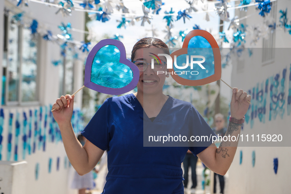 A woman is holding blue hearts made of cellophane paper while participating in a cultural activity as part of World Autism Awareness Day in...