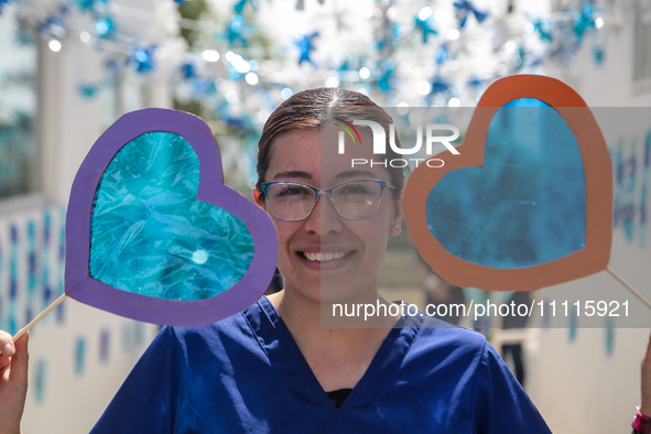 A woman is holding blue hearts made of cellophane paper while participating in a cultural activity as part of World Autism Awareness Day in...