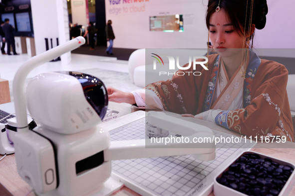 A woman is wearing traditional Chinese clothing and is playing Go with SenseRobot Go, a robot designed by SenseTime to play board games like...