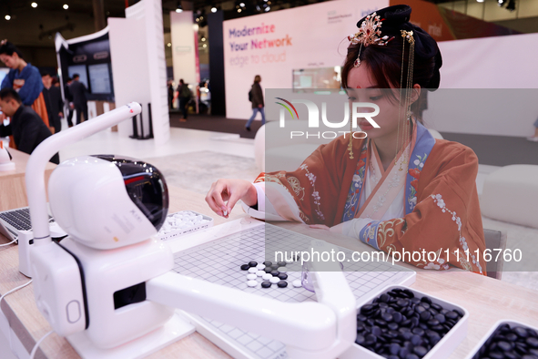 A woman is wearing traditional Chinese clothing and is playing Go with SenseRobot Go, a robot designed by SenseTime to play board games like...