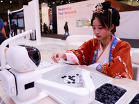 A woman is wearing traditional Chinese clothing and is playing Go with SenseRobot Go, a robot designed by SenseTime to play board games like...