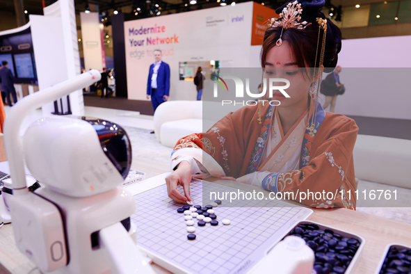 A woman is wearing traditional Chinese clothing and is playing Go with SenseRobot Go, a robot designed by SenseTime to play board games like...