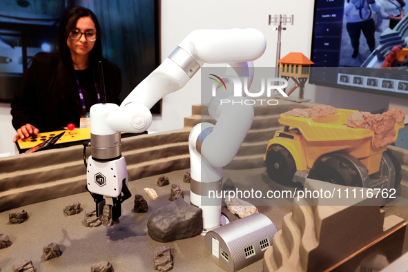 A woman is operating the xARM 5 Lite Robotic Arm in a construction excavation model using 5G technology at the DELL pavilion during the Mobi...