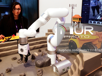 A woman is operating the xARM 5 Lite Robotic Arm in a construction excavation model using 5G technology at the DELL pavilion during the Mobi...