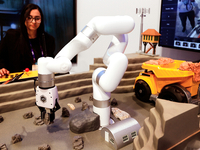 A woman is operating the xARM 5 Lite Robotic Arm in a construction excavation model using 5G technology at the DELL pavilion during the Mobi...