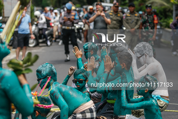 Balinese men with painted bodies are praying as they attend the Ngerebeg tradition in Tegallalang Village, Bali, Indonesia, on April 3, 2024...