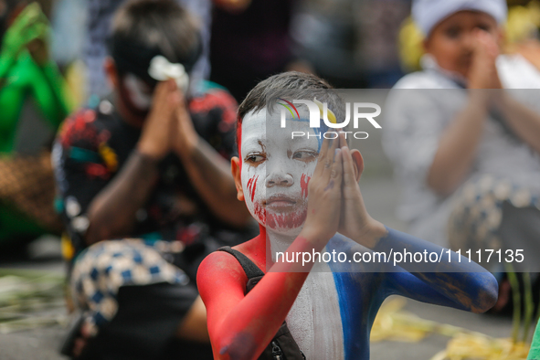 A Balinese child with a painted body is praying as they participate in the Ngerebeg tradition in Tegallalang Village, Bali, Indonesia, on Ap...