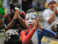 A Balinese child with a painted body is praying as they participate in the Ngerebeg tradition in Tegallalang Village, Bali, Indonesia, on Ap...
