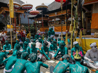 Balinese men with painted bodies are eating together as they attend the Ngerebeg tradition in Tegallalang Village, Bali, Indonesia, on April...