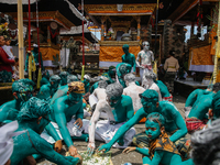 Balinese men with painted bodies are eating together as they attend the Ngerebeg tradition in Tegallalang Village, Bali, Indonesia, on April...