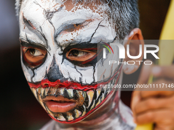 A Balinese child with a painted body is waiting while attending the Ngerebeg tradition in Tegallalang Village, Bali, Indonesia, on April 3,...