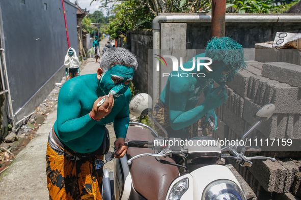 Balinese men are being painted before they attend the Ngerebeg tradition in Tegallalang Village, Bali, Indonesia, on April 3, 2024. Ngerebeg...