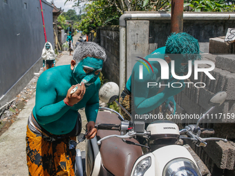 Balinese men are being painted before they attend the Ngerebeg tradition in Tegallalang Village, Bali, Indonesia, on April 3, 2024. Ngerebeg...