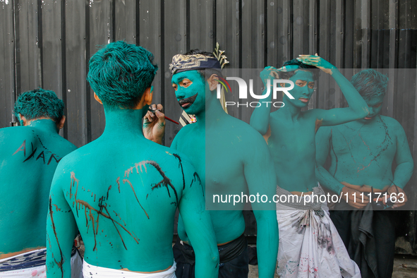 Balinese men are being painted before they attend the Ngerebeg tradition in Tegallalang Village, Bali, Indonesia, on April 3, 2024. Ngerebeg...