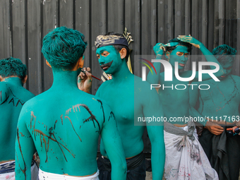 Balinese men are being painted before they attend the Ngerebeg tradition in Tegallalang Village, Bali, Indonesia, on April 3, 2024. Ngerebeg...