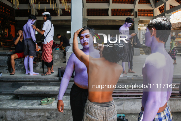 Balinese men are being painted before they attend the Ngerebeg tradition in Tegallalang Village, Bali, Indonesia, on April 3, 2024. Ngerebeg...