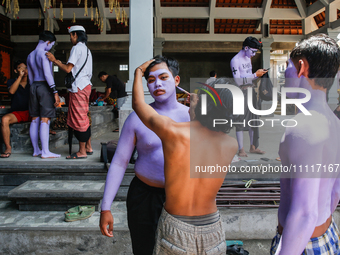 Balinese men are being painted before they attend the Ngerebeg tradition in Tegallalang Village, Bali, Indonesia, on April 3, 2024. Ngerebeg...