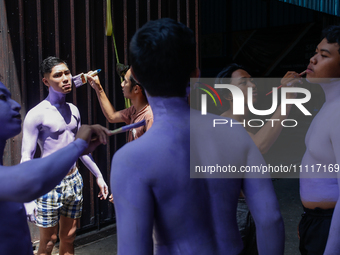 Balinese men are being painted before they attend the Ngerebeg tradition in Tegallalang Village, Bali, Indonesia, on April 3, 2024. Ngerebeg...