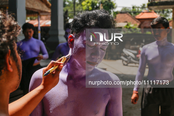 Balinese men are being painted before they attend the Ngerebeg tradition in Tegallalang Village, Bali, Indonesia, on April 3, 2024. Ngerebeg...