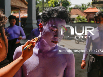 Balinese men are being painted before they attend the Ngerebeg tradition in Tegallalang Village, Bali, Indonesia, on April 3, 2024. Ngerebeg...