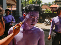 Balinese men are being painted before they attend the Ngerebeg tradition in Tegallalang Village, Bali, Indonesia, on April 3, 2024. Ngerebeg...